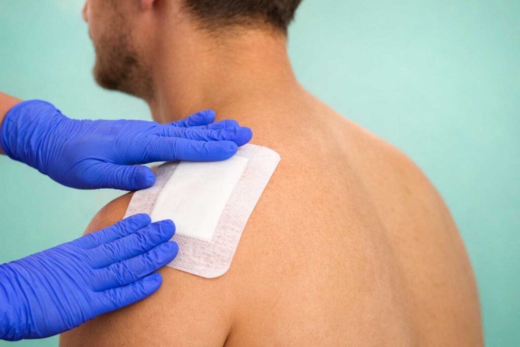 Medical provider treating a wound on a man's shoulder